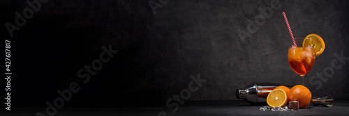 Cocktail. Glass of cold beverage, ice, oranges, bar accessories on dark grey background with copy space. Cocktail Aperol spritz