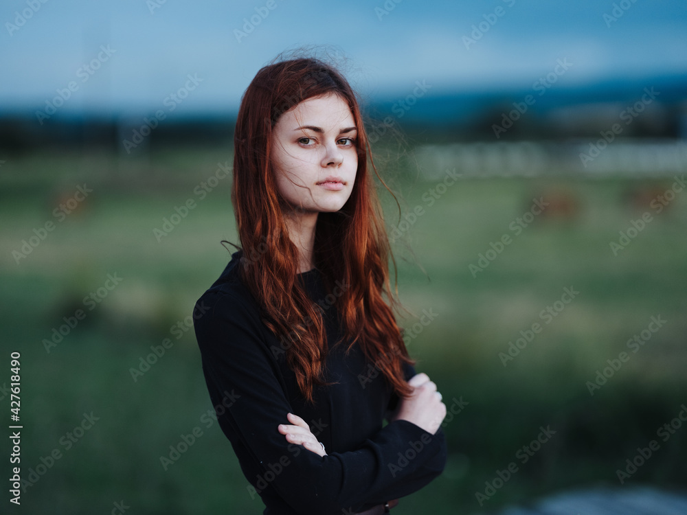 Red-haired Woman in black dress on nature outdoors blue sky model Red-haired Woman in black dress on nature outdoors blue sky model