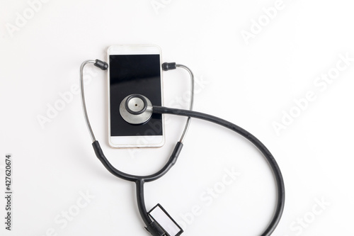 Smartphone and stethoscope on white background. Online medicine (telemedicine) technology. Service for remote diagnostic, chat with doctor.
