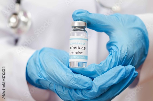 Doctor or laborant in protective gloves holding ampule tube with nCoV Coronavirus vaccine for COVID virus.