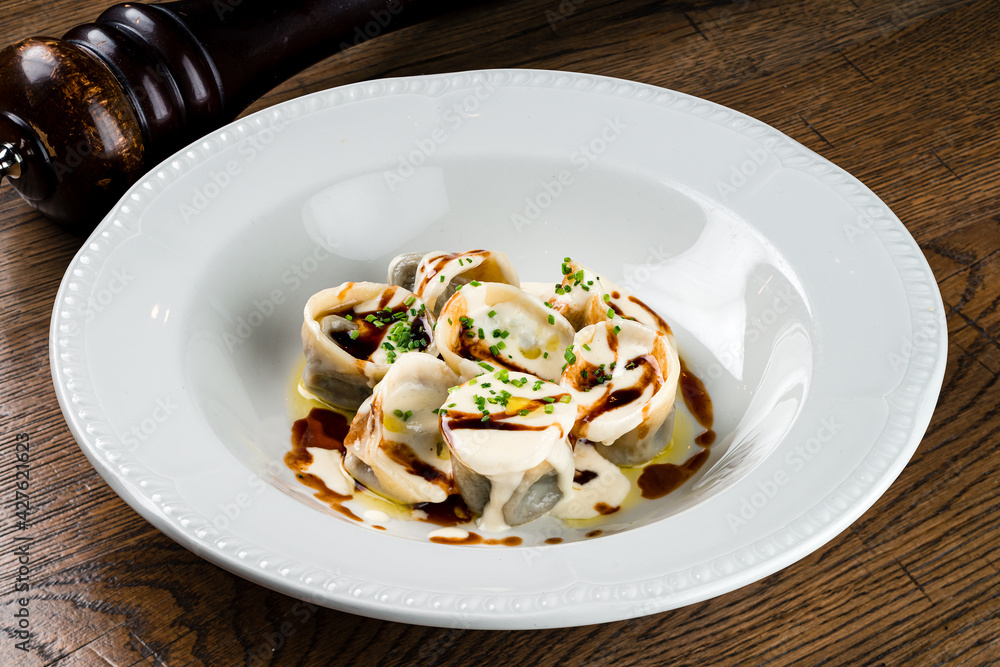italian ravioli filled with ricotta cheese smothered in a creamy sauce on a dark background