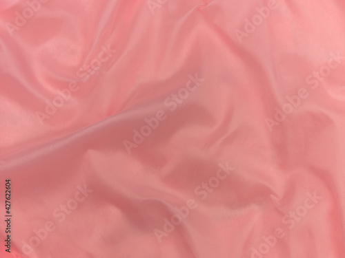 Pink silk fabric texture top view. Red coral glossy satin background. Fashion color feminine clothes trend. Female blog backdrop text sign design.Girly abstract wallpaper smooth textile surface.