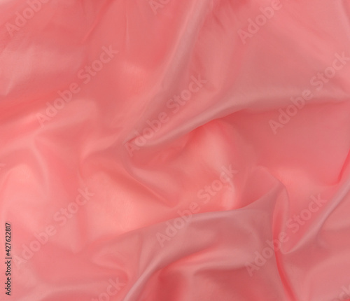 Pink silk fabric texture top view. Red coral glossy satin background. Fashion color feminine clothes trend. Female blog backdrop text sign design.Girly abstract wallpaper smooth textile surface. photo