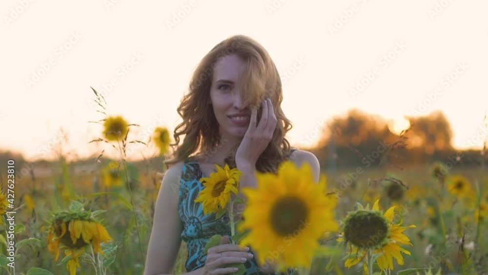 portrait of a young attractive woman with red hair and a blue dress in a field of sunflowers at sunset. Beautiful model against the backdrop of the setting rays of the sun portrait of a young attractive woman with red hair and a blue dress in a field of sunflowers at sunset. Beautiful model against the backdrop of the setting rays of the sun