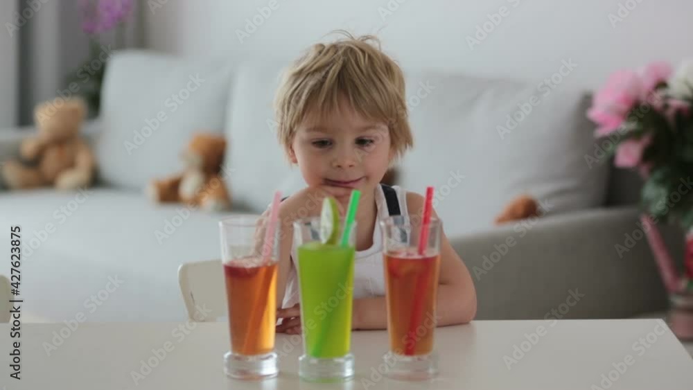 Cute toddler child, blond boy, drinking freshly made fruit juice at home, four glasses full of fresh juice Cute toddler child, blond boy, drinking freshly made fruit juice at home, four glasses full of fresh juice