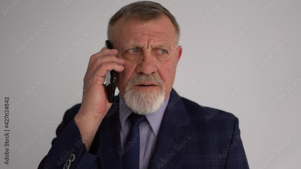 Close portrait of a mature successful businessman. Serious gray-bearded man in business suit talking on the phone Close portrait of a mature successful businessman. Serious gray-bearded man in business suit talking on the phone