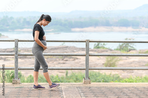 Portrait of young Asian pregnant woman walking and workout in the park.