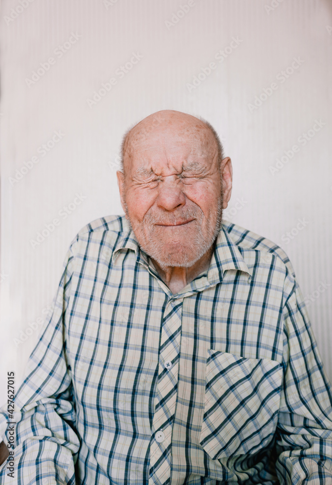 Obraz premium a large portrait of an old man on a light background with deep wrinkles, age spots.