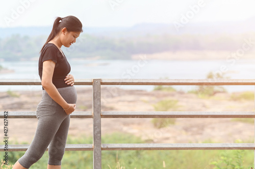 Portrait of young Asian pregnant woman walking and workout in the park. © nuttapon