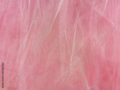Pink tulle fabric texture top view. Coral background. Fashion rose color trendy feminine tutu skirt flat lay, female blog glossy backdrop for text sign design. Girly abstract wallpaper,textile surface