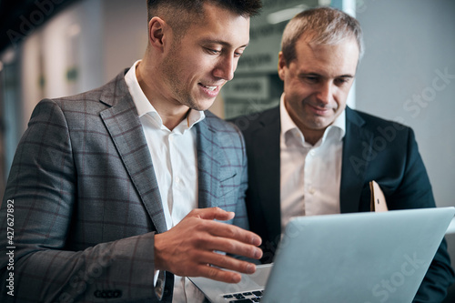 Joyful business colleagues using laptop at work