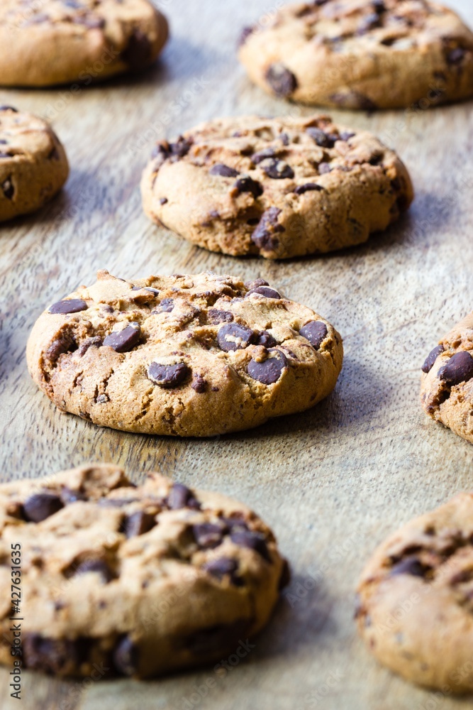 Freshly bakes chocolate chip cookies on wooden board arranged in slightly diagonal lines