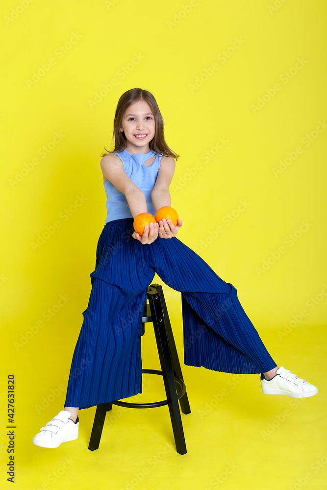 Cute little playful funny girl happily holding orange oranges, in the background Cute little playful funny girl happily holding orange oranges, in the background