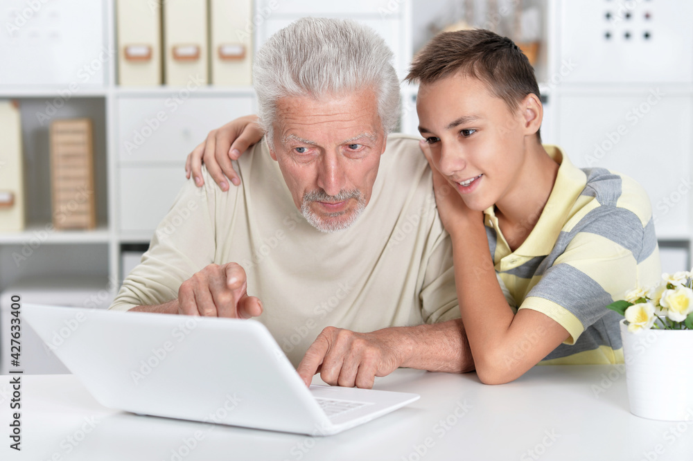 portrait of  boy and  grandfather with a laptop at home