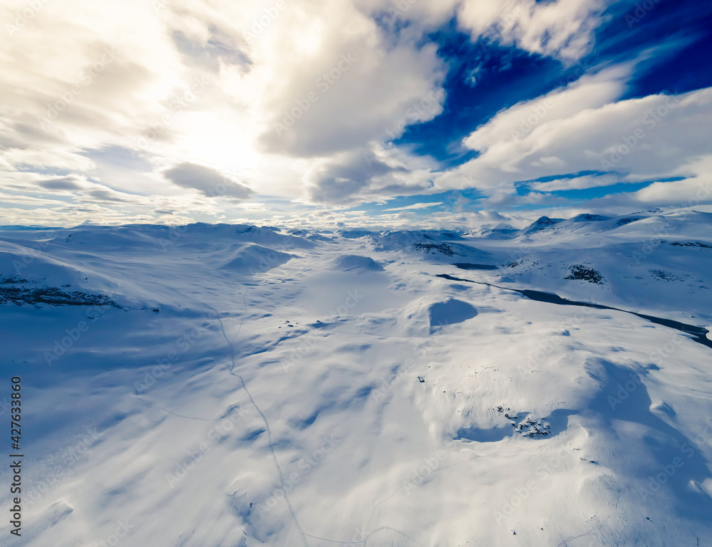 Spectacular panoramic view over snowcapped mountain peaks, ridges and frozen highland tundra in Jotunheimen, Norway.