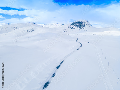 Lonely frozen road winding through a snow covered mountain landscape on a cold winters day.