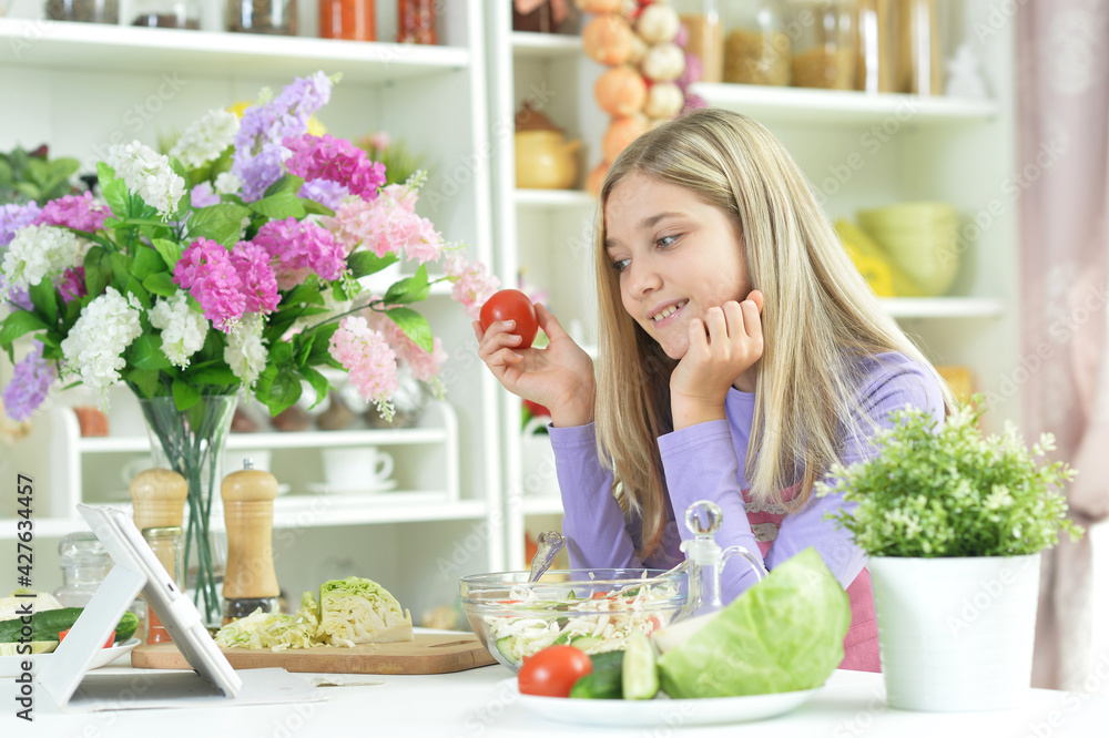 Cute little girl holding tomato and looking at tablet Cute little girl holding tomato and looking at tablet