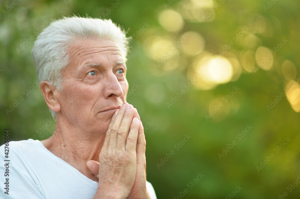 portrait of senior man in park praying portrait of senior man in park praying