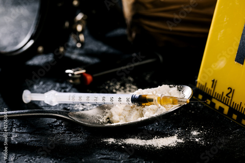Heroin in a syringe and heroin powder on a black background. the concept of a narcotic substance