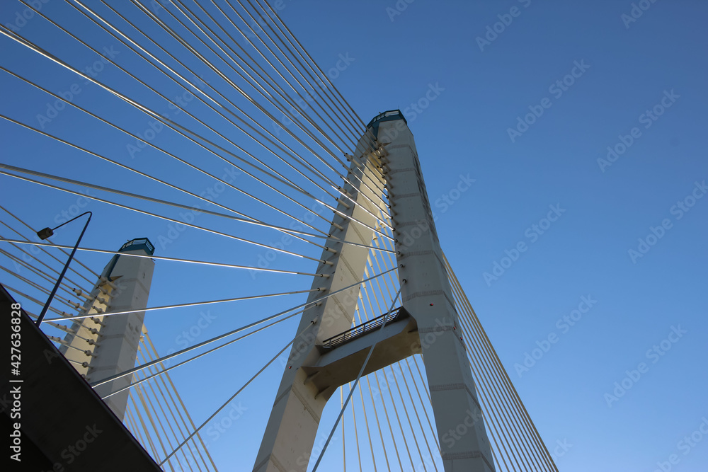 Obraz premium Bottom view of the cable-stayed bridge supports and cable stays against the sky 