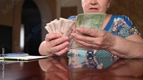 Close up of alderly woman counts banknotes euro leads budget checks money savings, pension payments photo