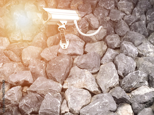 Outdoor security camera. Security camera mounted on a stone wall against with sunlight flare.