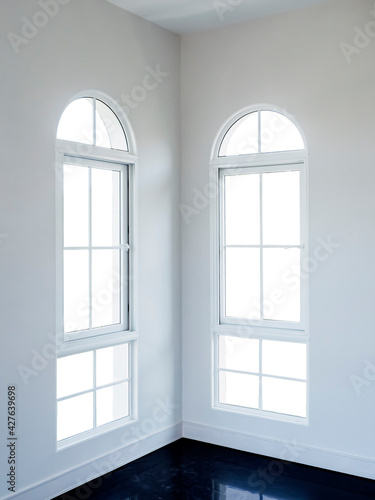 Two half-moon windows white frame at white room corner with white backgrounds. Interior empty room wall and windows in a luxury house.