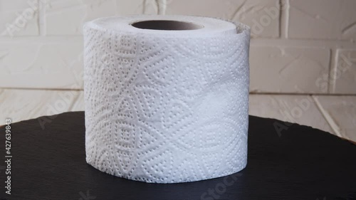 Toilet paper roll rotating on a black background. Presentation of toilet paper roll