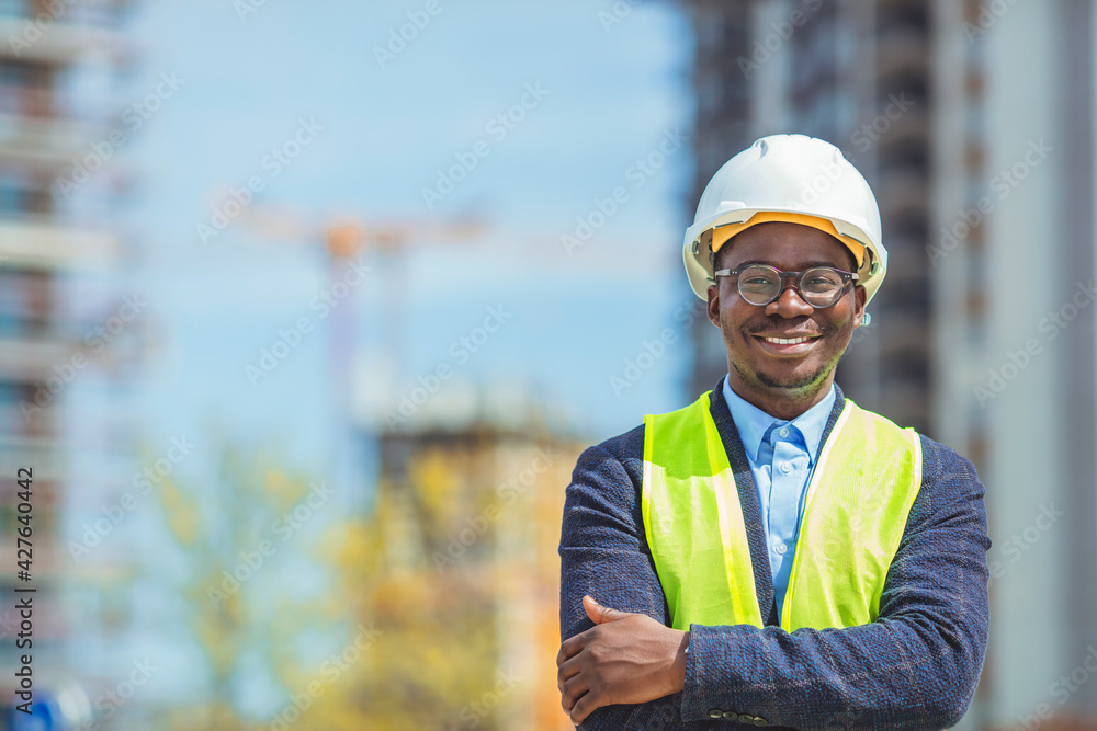 Architect at building site with folded arms looking at camera. Confident construction manager in formal clothing wearing blue hardhat. Successful mature civil engineer at construction site Architect at building site with folded arms looking at camera. Confident construction manager in formal clothing wearing blue hardhat. Successful mature civil engineer at construction site