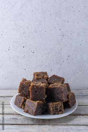 plate of dodol on a wooden table, also called kalu dodol, sri lankan dark sweet candy, made from coconut milk, jaggery and rice flour, sticky, thick, sweet toffee photo