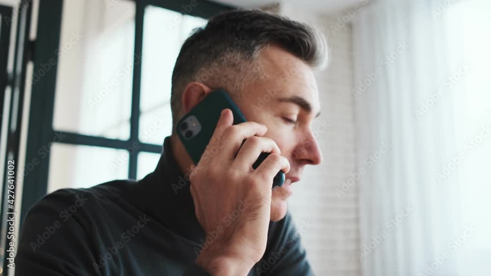 The mature man talking on the phone in bright room The mature man talking on the phone in bright room