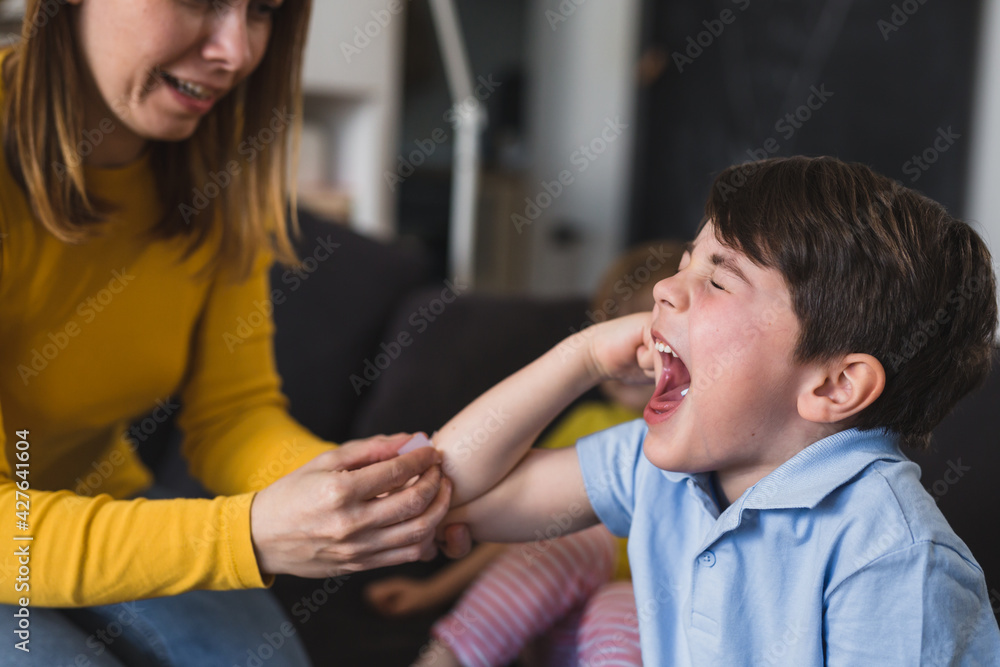 mother applying bandage to her sons elbow mother applying bandage to her sons elbow