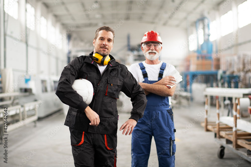Portrait of workers in factory. Colleagues with helmet working in factory Portrait of workers in factory. Colleagues with helmet working in factory