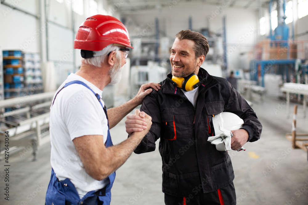 Portrait of workers in factory. Colleagues with helmet working in factory Portrait of workers in factory. Colleagues with helmet working in factory