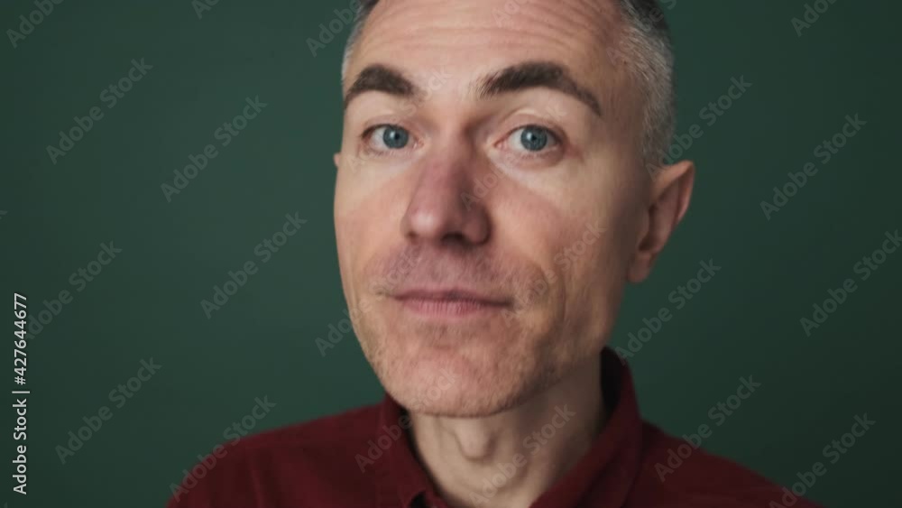 A close-up view of a confident elder man is pointing to the viewer standing isolated over green background in the studio A close-up view of a confident elder man is pointing to the viewer standing isolated over green background in the studio