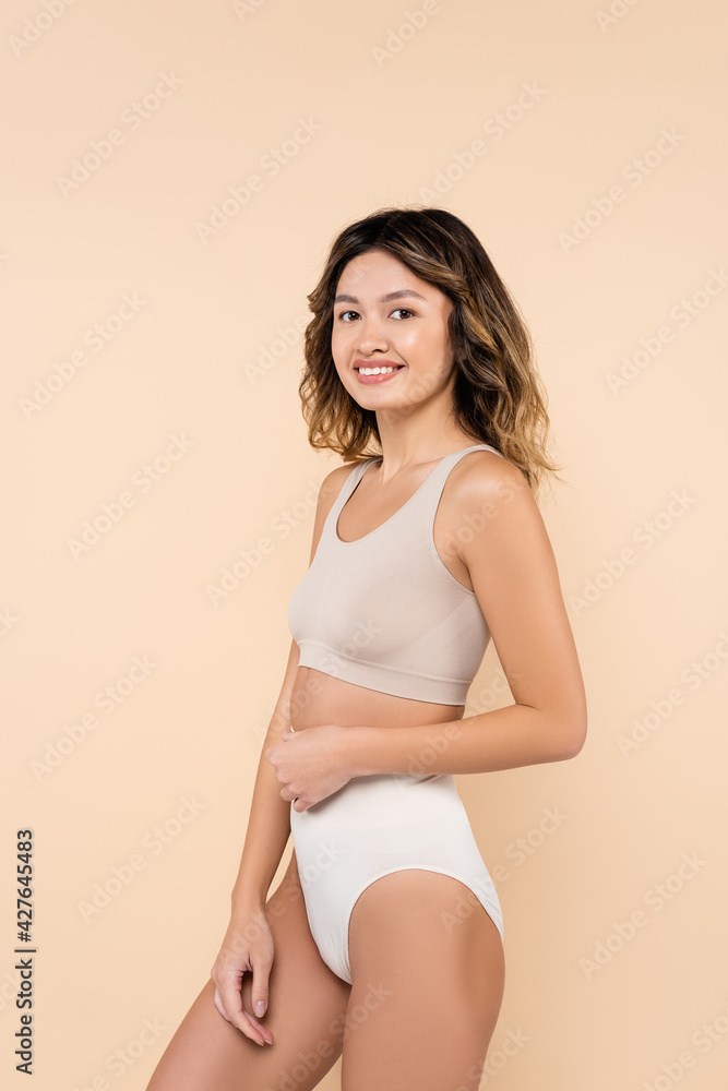 pleased asian woman in underwear smiling at camera isolated on beige pleased asian woman in underwear smiling at camera isolated on beige