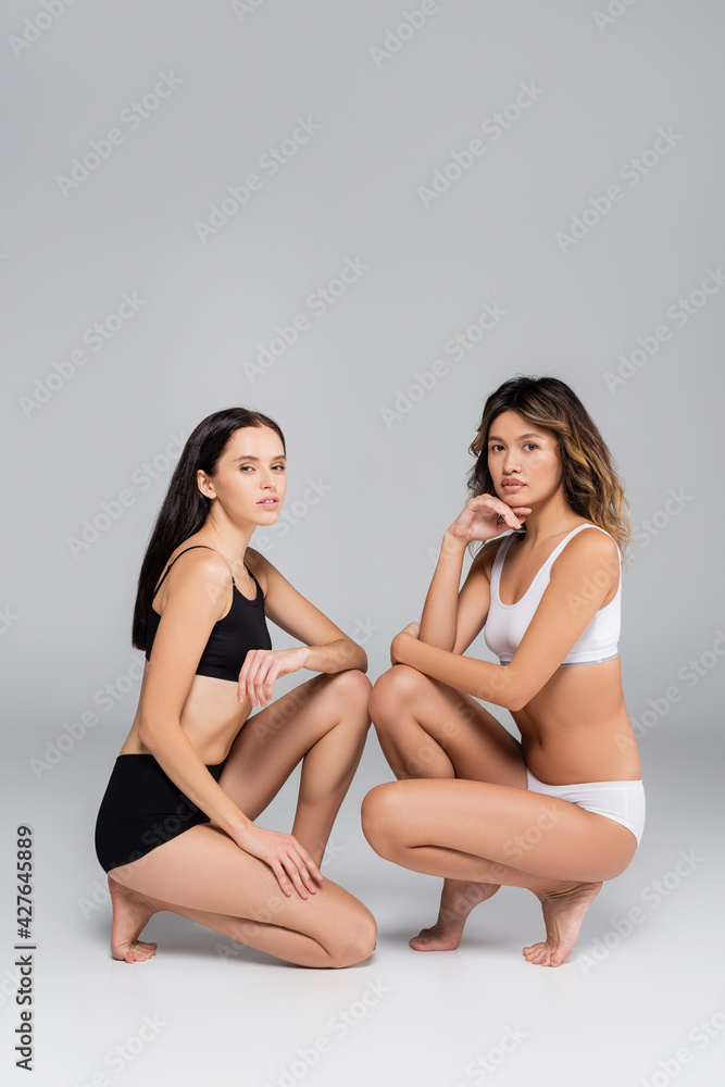 young multiethnic women with perfect bodies posing in underwear on grey