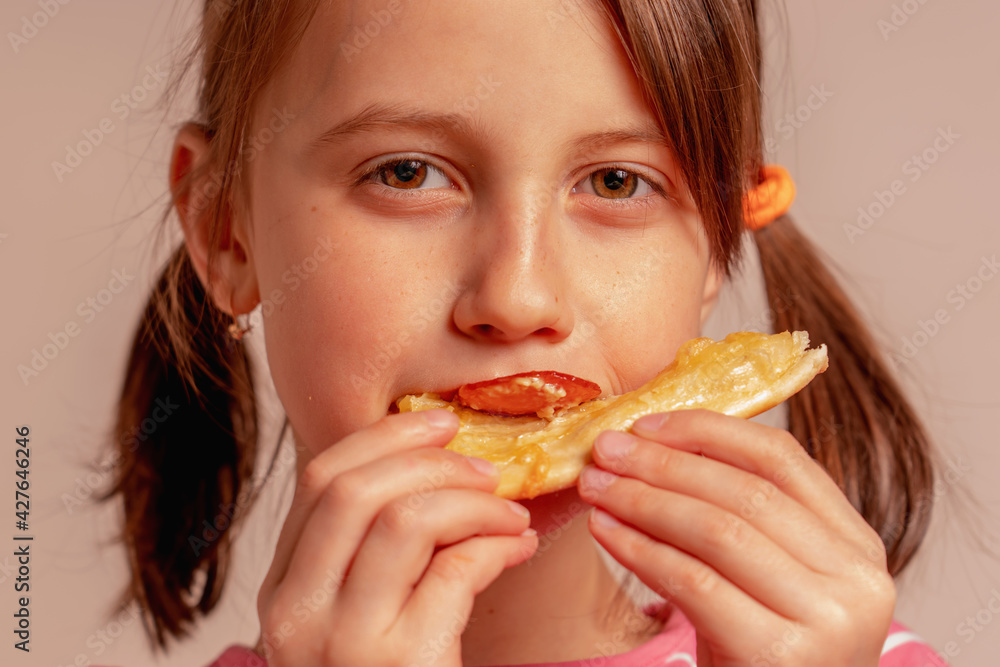 Happy beautiful young girl is eating a piece of pizza