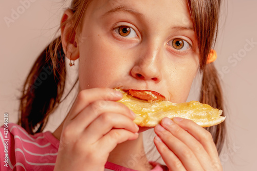 Portrait of happy beautiful young girl is eating a piece of pizza.