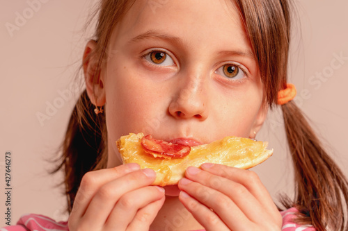 A young girl is eating a piece of pizza