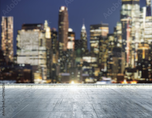 Empty concrete dirty rooftop on the background of a beautiful blurry New York city skyline at night, mock up © Pixels Hunter