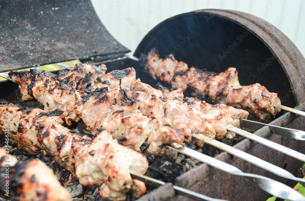 Selective focus on barbecues on grill. Skewers with meat lie over coals.  Tasty meat is fried on charcoal. Summer BBQ picnic concept. Fragrant smoke over grilled meat.