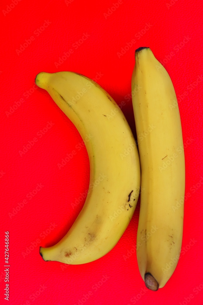 Yellow banana tropical fruit on red background or texture