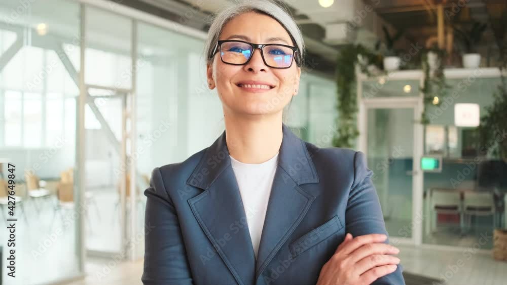 A beautiful elder businesswoman is standing in a confident pose in a hall A beautiful elder businesswoman is standing in a confident pose in a hall