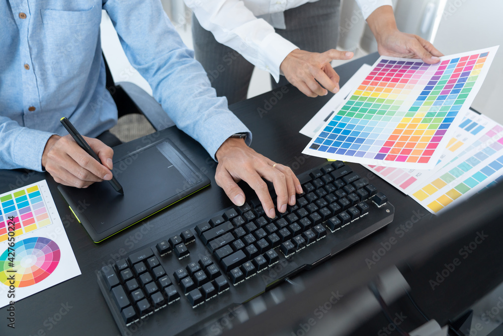 graphic designer team working on web design using color swatches editing artwork using tablet and a stylus at desks In creative office graphic designer team working on web design using color swatches editing artwork using tablet and a stylus at desks In creative office