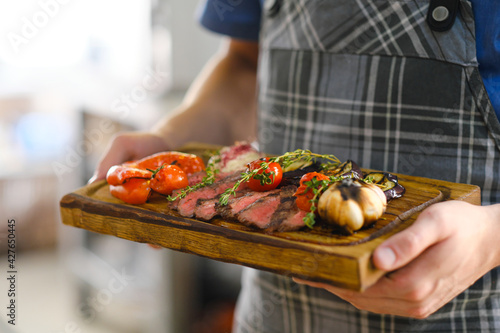 Freshly cooked meat and grilled vegetables. Ready food on a wooden board.
