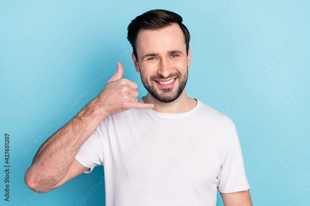 Portrait of attractive cheerful guy showing call me sign answer isolated over blue bright pastel color background Portrait of attractive cheerful guy showing call me sign answer isolated over blue bright pastel color background