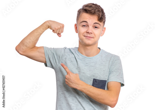 Portrait of funny teen boy raised his hand and shows biceps, isolated on white background. Handsome teenage young boy shows biceps.