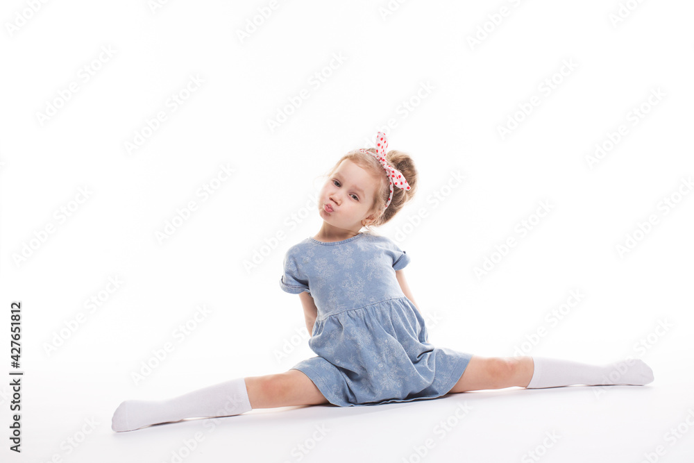 Childhood, emotions concept, little cute girl in a blue dress posing in the studio on a white Childhood, emotions concept, little cute girl in a blue dress posing in the studio on a white