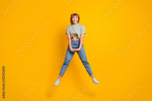 Full length body size view of charming cute modest cheerful girl jumping having fun isolated over bright yellow color background
